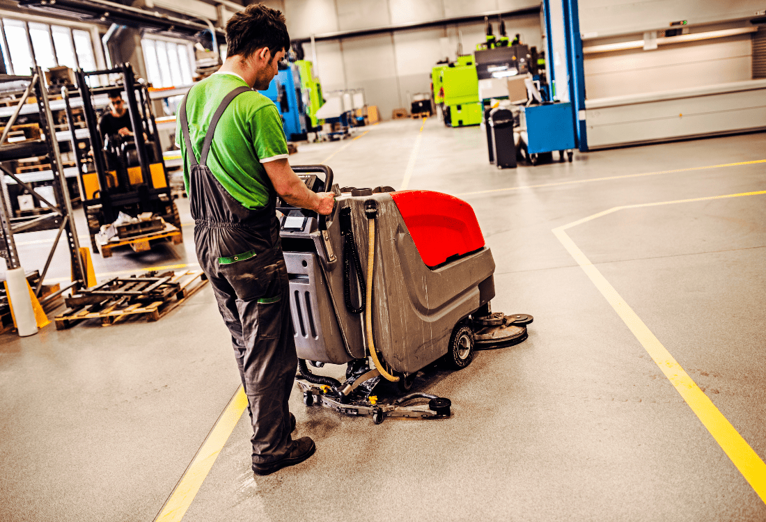 Worker cleaning hygienic resin flooring with a cleaning buffer in a factory